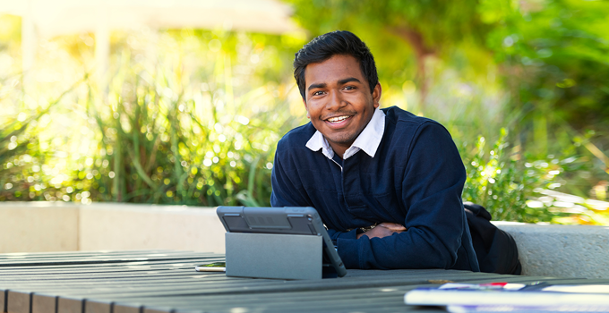 Image of student sitting at bench with an iPad open
