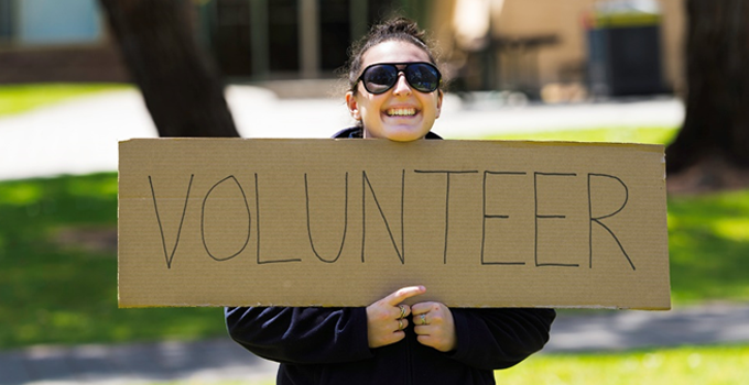 image of student holding "Volunteer" sign