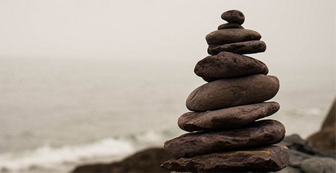 Image of stacked rocks against an ocean background.