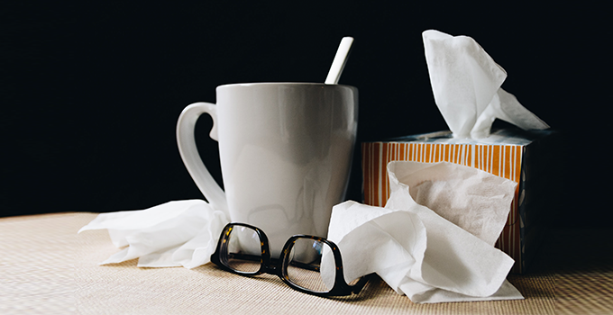 Image of a cup of tea, tissues, and glasses