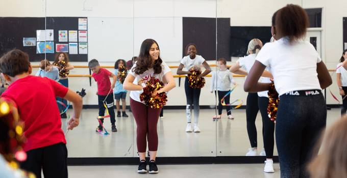 Image of Alana teaching a cheer routine to a class of kids
