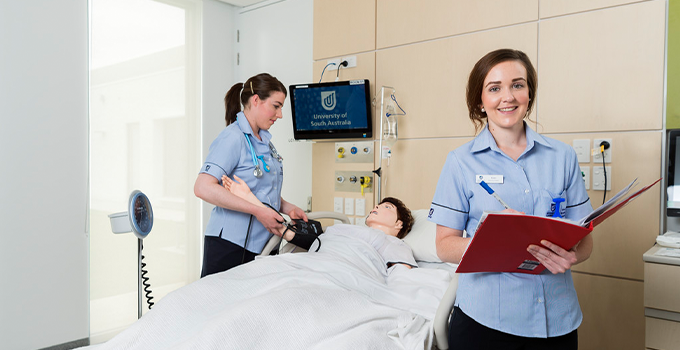 Two female nursing students training with a simulation mannequin at a UniSA clinic.