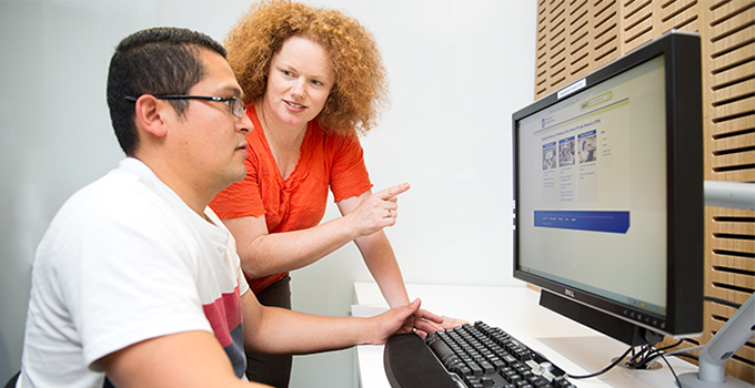 Access and Inclusion adviser working with student at a computer monitor
