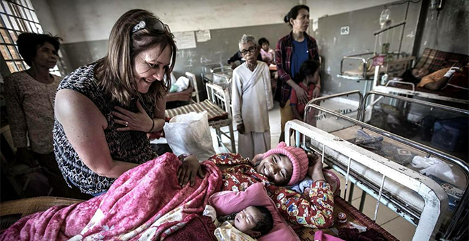 Image of Kate Taylor caring for a mother and her new born at a Cambodian medical clinic.