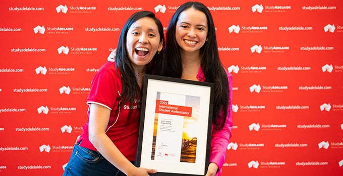 Two female students holding a certificate from the StudyAdelaide Awards