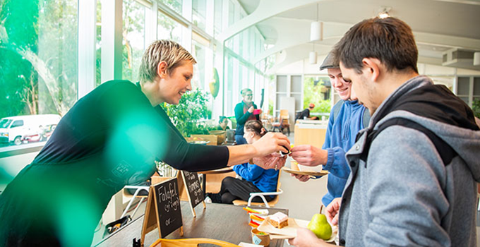 Image of person handing out breakfast at an event held at student lounge.
