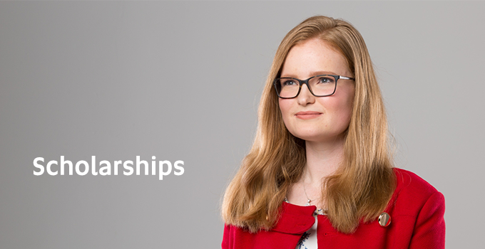 Corporate headshot of female student with long hair, wearing a red jacket and glasses