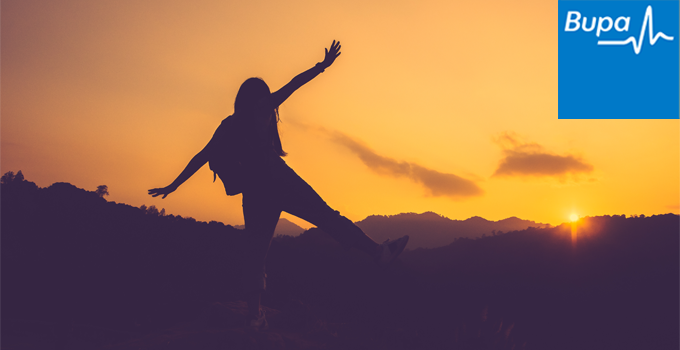 Silhouette image of person dancing in nature with sunset sky in the background and Bupa logo in top right corner.
