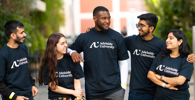 Photo of five students wearing Adelaide University T-shirts on campus.