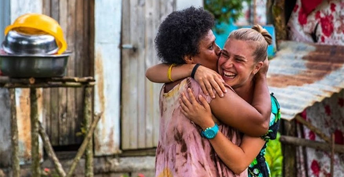 Image of female Pacific Islander hugging female volunteer helping her community.