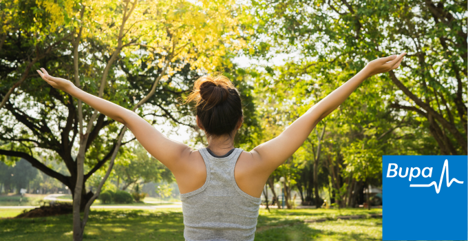 Image of a female at a park stretching her arms up with her back to the camera