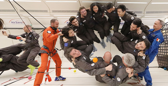 Image of participants huddled in a circle taking part in a zero gravity activity.