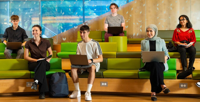 Image of students sitting in the JS Forum with their laptop or notebook listening to a presentation