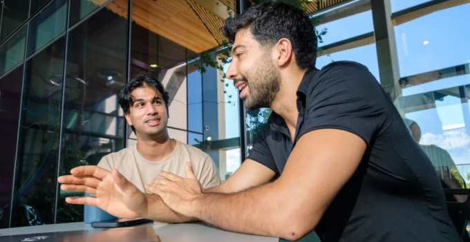 Image of two students having a discussion while browsing on the laptop