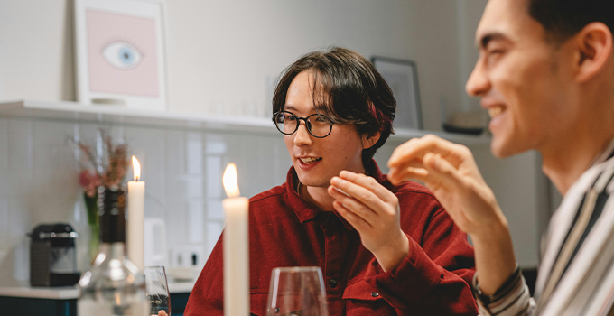 Image of two young males conversing and having dinner in indoor setting.