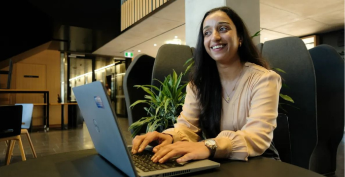 Photo of a female student with a laptop, looking excited.
