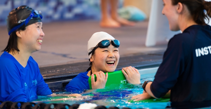 Two students laughing with instructor in the water of Pridham Hall pool