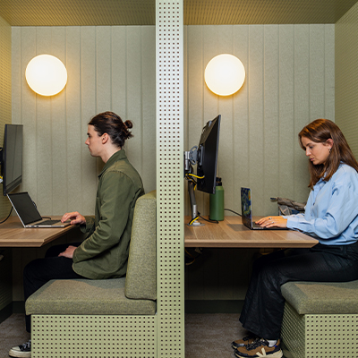 Photo of two students studying in their own study nooks on campus.