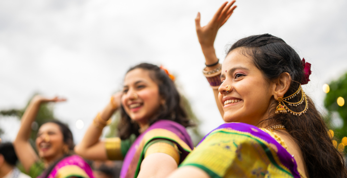 Close up shot of three female students in traditional attire dancing at Diwali celebration.