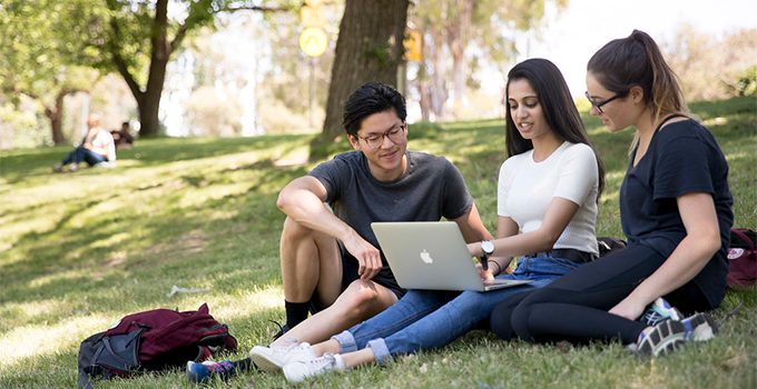 Image of three students studying on laptop outdoors