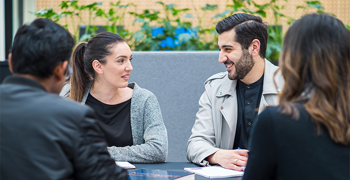 Image of male and female students in a discussion sitting around a table