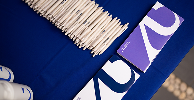 Adelaide University pamphlets, pens and drink bottles on a table.