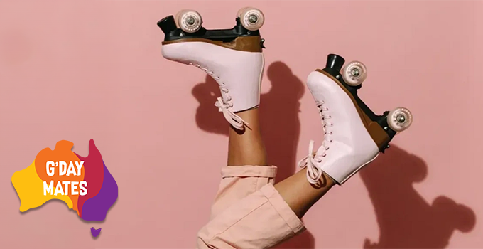 Close up shot of a person's legs hanging upside down in the air, wearing cream pink rollers skates against pastel background.