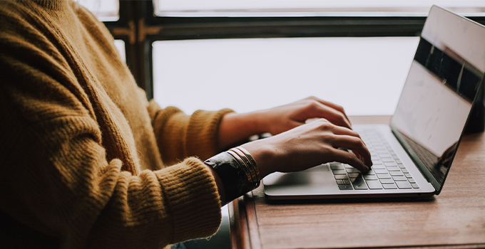 Close up photo of person typing on their laptop.