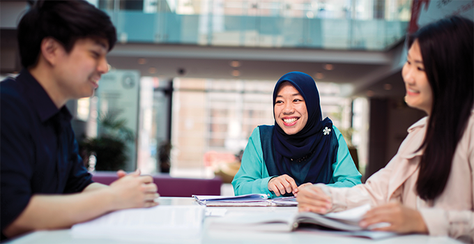 Image of one male and two female students studying together