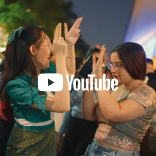 Photo of two students in traditional cultural dresses dancing at the Multicultural Fest, with YouTube logo as an overlay on the image
