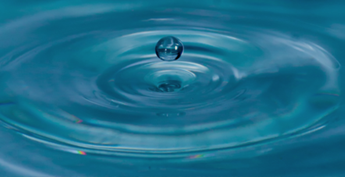 Macro image of droplet of water hitting a pond