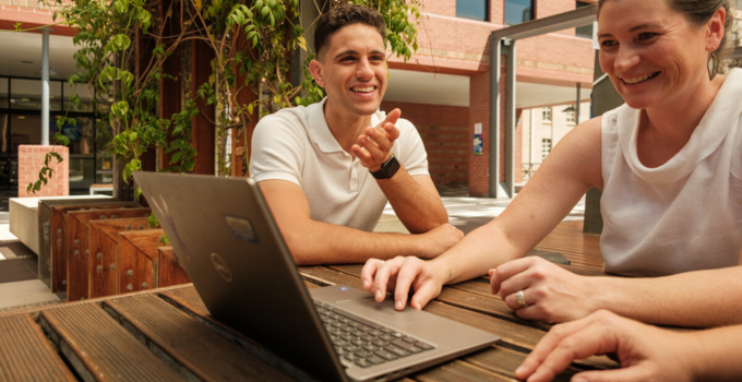 Image of students chatting and browsing on a laptop