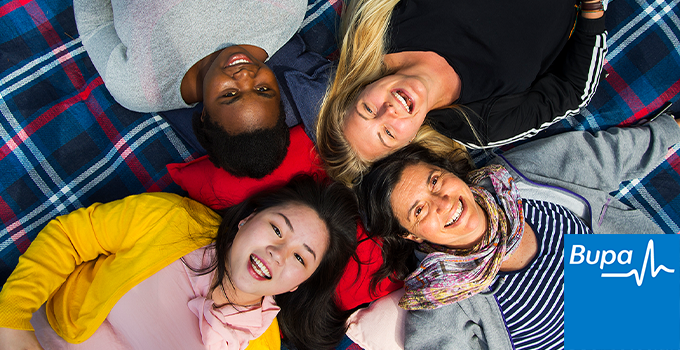 Students lying in a circle down on picnic rug and smiling into the camera